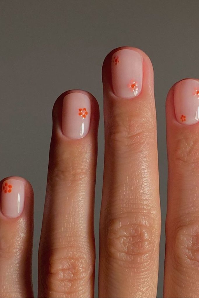 Idées d'ongles de vacances : base nue avec des fleurs délicates et lumineuses