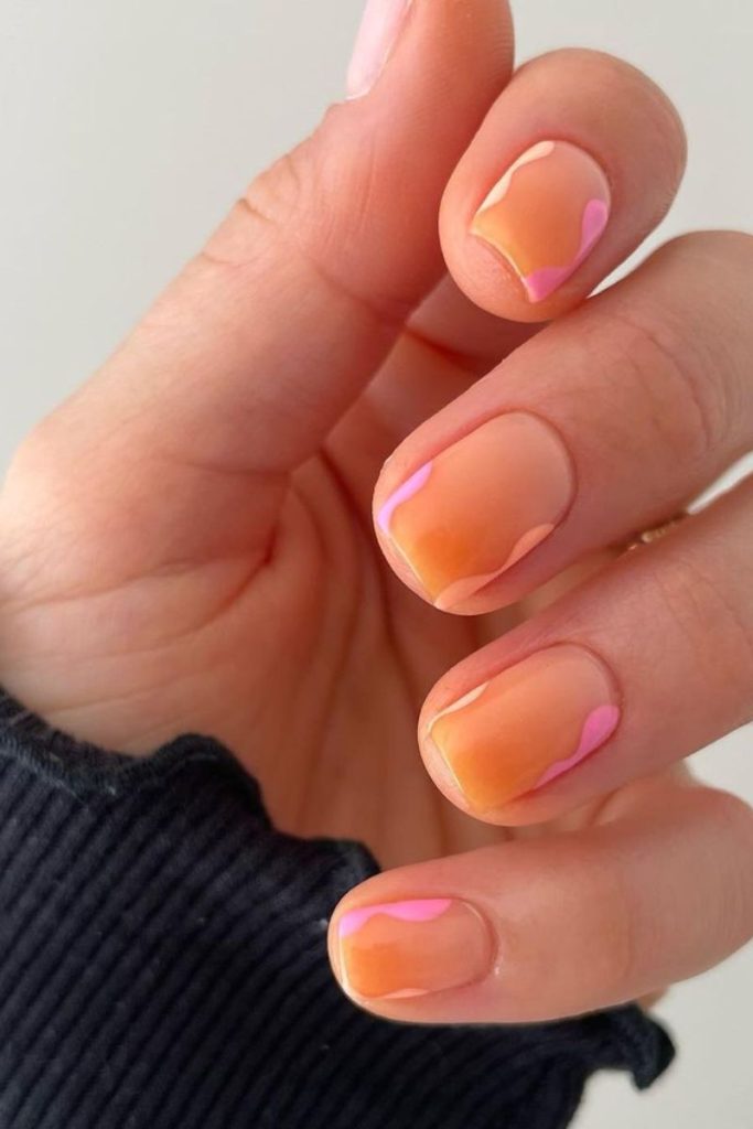 Idées d'ongles de vacances : pointes orange ombré avec des tourbillons roses et oranges